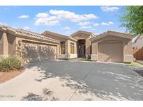 Tan home exterior showcasing a well-maintained yard, a three-car garage, and a welcoming entrance under a sunny sky at 4667 E County Down Dr, Chandler, AZ 85249