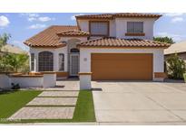 Inviting two-story home with a well-maintained yard and a two-car garage with a pathway to the front door at 5211 W Wikieup Ln, Glendale, AZ 85308