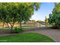 Landscaped backyard features a pond view and wrought iron fence at 6907 W Monona Dr, Glendale, AZ 85308