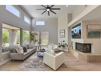 Bright living room with a fireplace, large windows, ceiling fan, and modern decor at 7128 E Bramble Berry Ln, Scottsdale, AZ 85266
