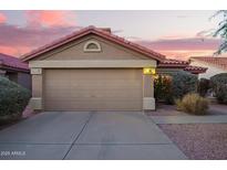 Home exterior showcasing a 2-car garage with a charming desert landscape and a red tile roof under a colorful evening sky at 8132 E Onza Ave, Mesa, AZ 85212