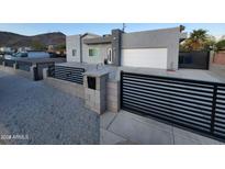 Contemporary home featuring a gray stucco exterior, gravel landscaping, black metal fence, and an attached two-car garage at 10637 N 16Th Ave, Phoenix, AZ 85029