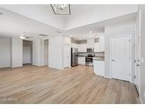 Bright, open-concept living space featuring wood-look floors and an adjacent kitchen with stainless steel appliances at 14870 W Encanto Blvd # 1091, Goodyear, AZ 85395