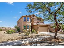 Charming two-story home with a tan facade, tiled roof, desert landscaping, and an attached two car garage at 18132 W Cardinal Dr, Goodyear, AZ 85338