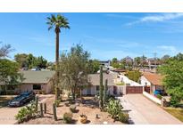 Charming home featuring desert landscaping, a tall palm tree, and a spacious driveway leading to a gated entrance at 1940 E Indianola E Ave, Phoenix, AZ 85016
