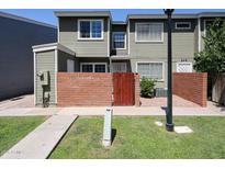 Two story townhome with well-manicured grass, a brick wall, and a wooden gate at 2301 E University Dr # 210, Mesa, AZ 85213