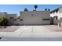 Exterior view of attached garage with mature landscaping and neutral color scheme at 4767 W Wahalla Ln, Glendale, AZ 85308