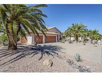 Charming front exterior featuring a three-car garage, desert landscaping, and mature palm trees on a sunny day at 4928 E Paradise Ln, Scottsdale, AZ 85254