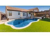 Private backyard oasis with a pool, synthetic grass and covered patio for relaxing at 11622 W Palm Brook Dr, Avondale, AZ 85392