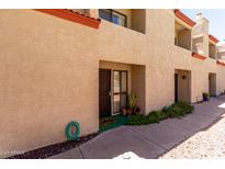 Townhouse exterior featuring a tan stucco facade, terracotta roof, and well-kept landscaping at 1401 E Puget Ave # 10, Phoenix, AZ 85020