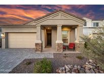 Inviting home exterior showcasing a covered entry with stone accents and desert landscaping, set against a vibrant sunset sky at 2324 E Saguaro Park Ln, Phoenix, AZ 85024