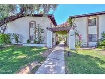 Inviting townhome with a lush green lawn, mature trees, and a charming pergola-covered entrance at 3637 E Monterosa St # 8, Phoenix, AZ 85018