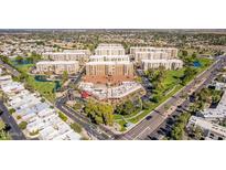 An aerial view of a condo complex surrounded by lush landscaping, mature trees, and a neighboring street at 7910 E Camelback Rd # 302, Scottsdale, AZ 85251