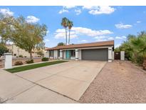 Charming single-story home with a well-maintained front yard, long driveway, and gray two car garage at 932 W Julie Dr, Tempe, AZ 85283