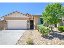 Charming home featuring a landscaped front yard, stone accents, and a two-car garage at 18027 W Tina Ln, Surprise, AZ 85387