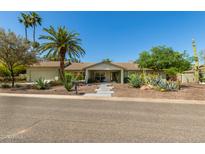 Charming single-story home with lush desert landscaping, mature trees, and inviting walkway at 6102 E Aster Dr, Scottsdale, AZ 85254
