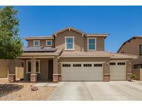 Two-story home featuring a three-car garage, desert landscaping, and solar panels for energy efficiency at 7858 W Fetlock Trl, Peoria, AZ 85383
