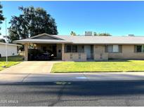 Charming single-story home featuring a carport, brick accents, and a well-maintained front lawn at 10726 W Kelso Dr, Sun City, AZ 85351