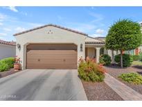 Charming home with a two-car garage, desert landscaping, and a tile roof under a blue sky at 14200 W Village Pkwy # 2128, Litchfield Park, AZ 85340