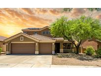Inviting two-story home featuring a three-car garage, desert landscaping, and a covered porch at 17493 W Arroyo Way, Goodyear, AZ 85338
