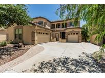 Beige stucco two-story home featuring an arched entryway, desert landscaping, and a 3-car garage with ample parking at 5437 W Red Bird Rd, Phoenix, AZ 85083