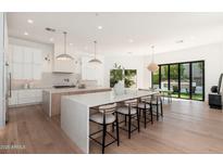 Bright, open kitchen featuring a large island, white cabinets, and modern lighting fixtures at 7710 E Tardes Dr, Scottsdale, AZ 85255