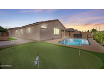 This backyard features a pool, putting green and patio, perfect for outdoor entertaining and relaxing at 21075 E Estrella Rd, Queen Creek, AZ 85142