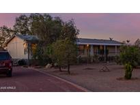 Home exterior featuring desert landscaping with mature plants, covered front porch, and gravel yard at 22216 W Bajada Dr, Wittmann, AZ 85361