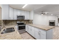 Updated kitchen with granite counters, stainless steel appliances, and a view of the fireplace at 4601 N 102Nd Ave # 1020, Phoenix, AZ 85037