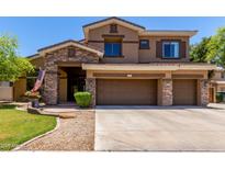 Two-story home with a three-car garage, stone accents, manicured lawn, and covered entryway at 723 E Gemini Pl, Chandler, AZ 85249