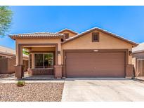 Charming single-story home featuring a two-car garage, desert landscaping, and a covered porch at 7419 W Raymond St, Phoenix, AZ 85043