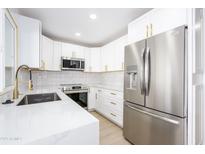 Bright kitchen features new stainless steel appliances, white cabinets, and gold hardware at 8341 E Keim Dr, Scottsdale, AZ 85250