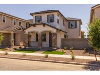 Charming two-story home featuring a cozy front porch with stone accents and a well-manicured front yard at 13465 N 158Th Ave, Surprise, AZ 85379