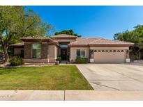 Charming single-story home boasts a lush lawn and a two-car garage with mature landscaping at 4037 E Elmwood St, Mesa, AZ 85205