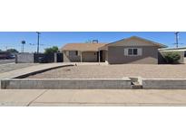 Modest single-story house featuring a neutral exterior, gravel yard, and classic desert landscaping at 4911 W Merrell St, Phoenix, AZ 85031