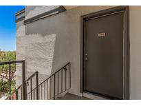 Exterior view of a grey front door with unit number and black handrail, on a bright day at 740 W Elm St # 266, Phoenix, AZ 85013