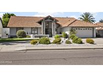 Charming single-story home showcasing a red tile roof, landscaped front yard, and inviting stone entryway at 1015 E Paradise Ln, Phoenix, AZ 85022