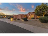 Inviting single-story home with a three-car garage and desert landscaping, illuminated beautifully against the sunset at 15600 E Robin Dr, Fountain Hills, AZ 85268