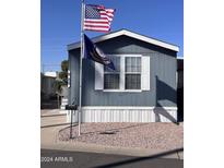Charming mobile home with blue siding, white trim, US and Navy flags flying at 2600 E Allred Ave # R-88, Mesa, AZ 85204
