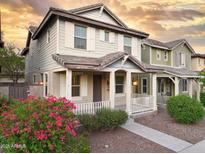 Charming two-story home featuring a cozy front porch, white railings, and beautiful, vibrant landscaping at 2947 N Evergreen St, Buckeye, AZ 85396