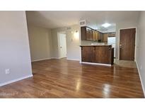 Open-concept living room and kitchen with wood-style floors and breakfast bar at 3131 W Cochise Dr # 256, Phoenix, AZ 85051