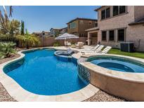 Inviting backyard pool with a built-in spa, lounge chairs, and lush landscaping at 5051 S Moccasin Trl, Gilbert, AZ 85298