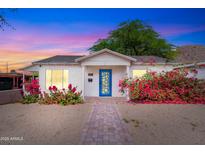 Charming white brick home with a vibrant blue door and beautiful bougainvillea bushes at 9520 N Central Ave, Phoenix, AZ 85020