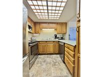 Bright kitchen features stainless steel appliances, wooden cabinetry, and a large skylight at 10330 W Thunderbird Blvd # C206, Sun City, AZ 85351
