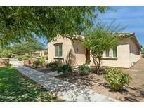 Inviting single-story home featuring lush green bushes and desert landscaping at 14844 W Pershing St, Surprise, AZ 85379