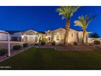 Charming single-story home with a three-car garage, desert landscaping, and illuminated palm trees at dusk at 20151 E Via Del Palo St, Queen Creek, AZ 85142