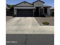 Single story home with a dark garage and neutral tones and rock landscaping at 2715 E Canyon Creek Dr, Gilbert, AZ 85295