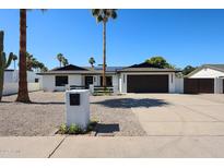 Charming single-story home features desert landscaping, dark trim, a two-car garage, and solar panels at 5259 E Karen Dr, Scottsdale, AZ 85254