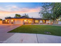 Charming single-story home with a well-manicured lawn and a two-car garage at sunset at 14221 N 43Rd St, Phoenix, AZ 85032