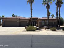 Beautiful single-story home featuring a lush landscaped front yard and a spacious three-car garage at 20332 N Denizen Dr, Surprise, AZ 85387